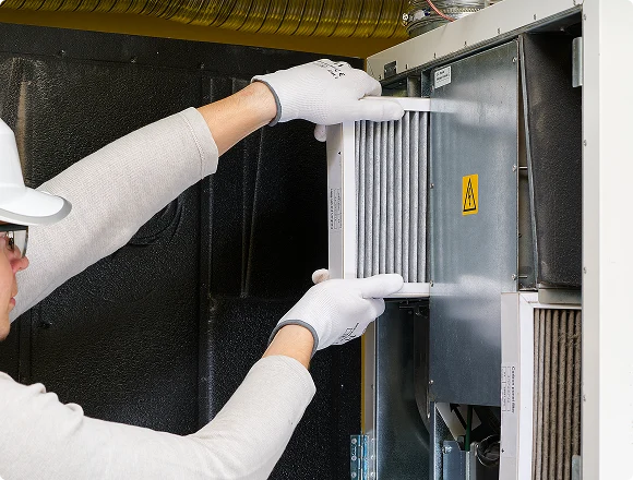 HVAC technician replacing an air filter inside a ventilation unit