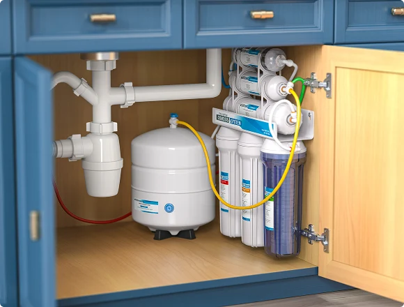 Under-sink view showing a reverse osmosis water filtration system with multiple filters and a storage tank, set against blue cabinetry. Clean and organized.