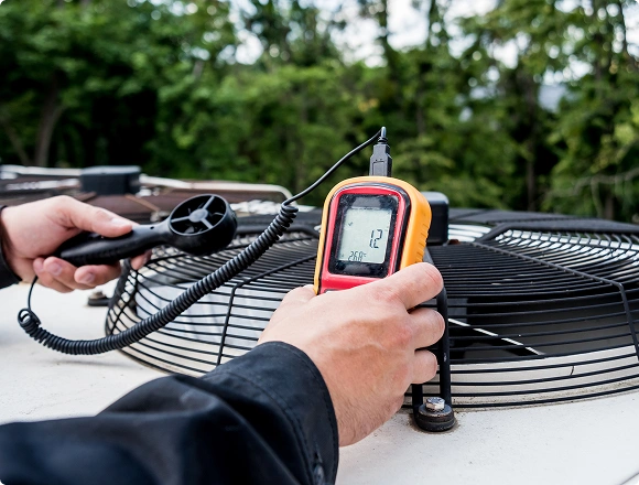 Technician measuring airflow from an outdoor air conditioner unit using an anemometer