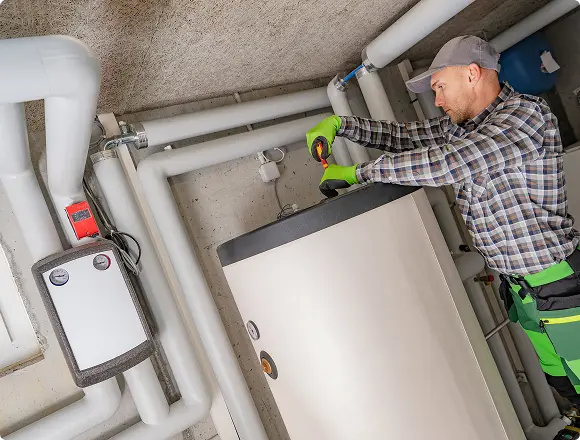 Technician repairing a large heating system with tools.