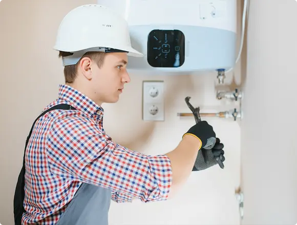 Technician installing a water heater connection with a wrench.