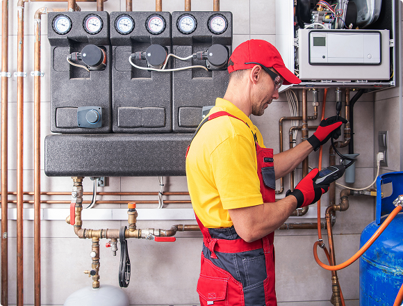 Technician checking pressure and system readings on a heating installation.