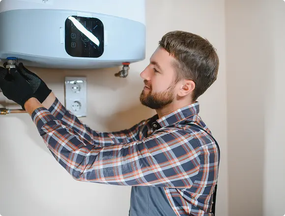 Technician adjusting a water heater unit indoors.