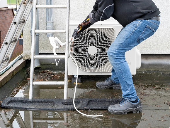 Technician performing maintenance on an outdoor air conditioner unit on a rooftop