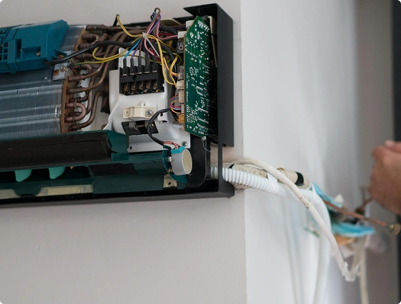 Exposed internal components and circuit board of a wall-mounted air conditioner during repair
