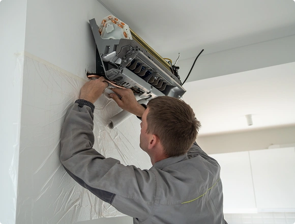 Technician repairing a wall-mounted air conditioner with the front panel removed