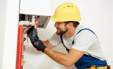 Technician repairing water heater pipes while wearing a safety helmet.