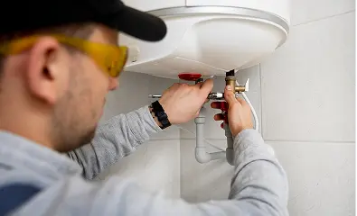 Technician adjusting pipes under a water heater.