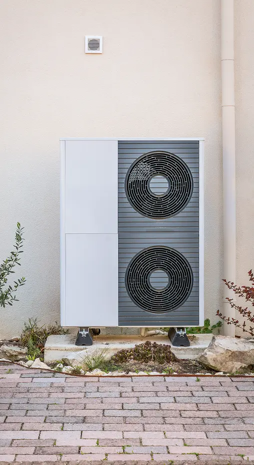 Outdoor heat pump unit installed next to a building wall.