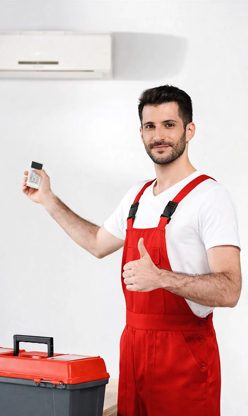 HVAC technician holding an air conditioner remote control and giving a thumbs-up after installation