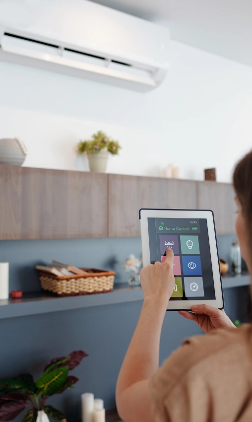 Woman controlling a wall-mounted air conditioner using a smart home tablet interface