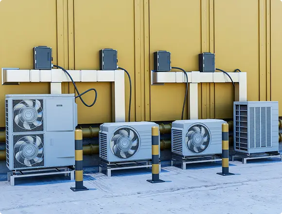 Multiple outdoor air conditioning units installed along a building wall with electrical connections.