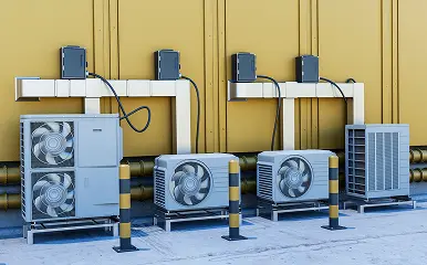 Multiple outdoor HVAC units installed along a building wall with visible piping and electrical connections.