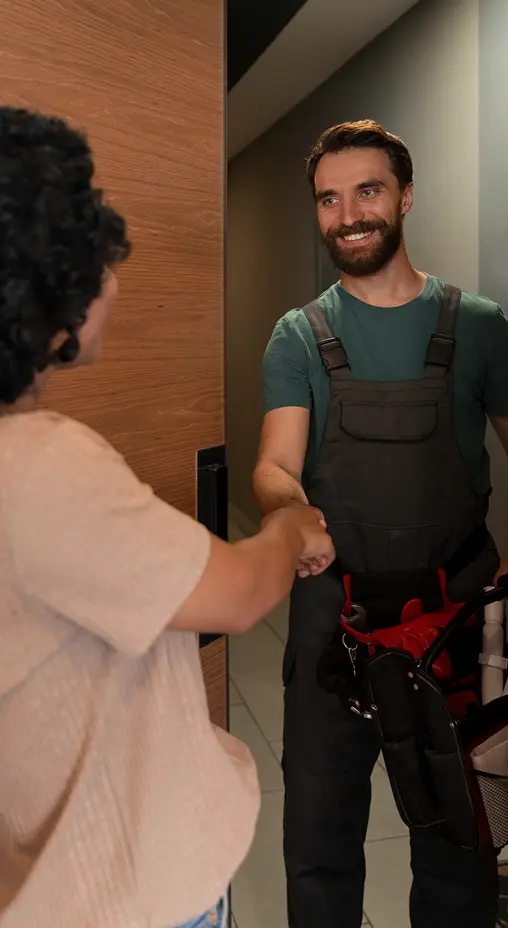 Service technician greeting a client at the door with a handshake, arriving for a maintenance or repair visit.
