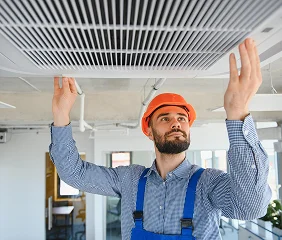Worker in hard hat adjusting ceiling ventilation panel