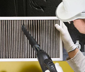 Worker vacuuming dirty ceiling air filter