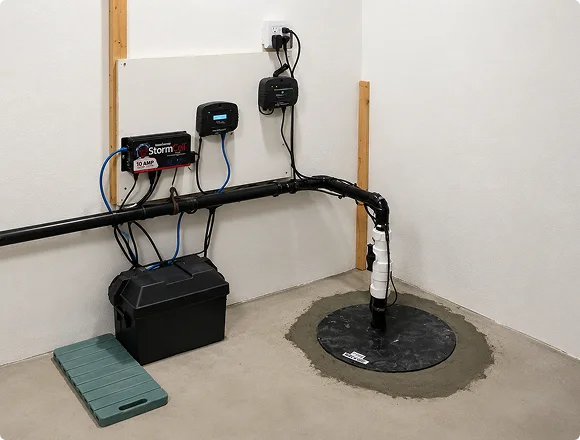 Installed sump pump system with battery backup and control panel in a basement