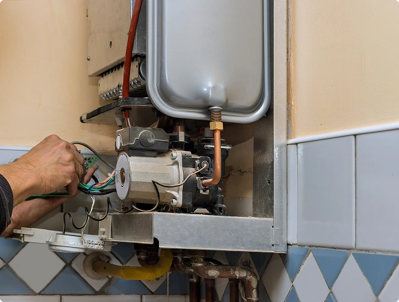 Technician repairing the internal components of a wall-mounted gas boiler