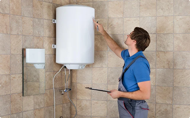 Technician inspecting a wall-mounted electric water heater
