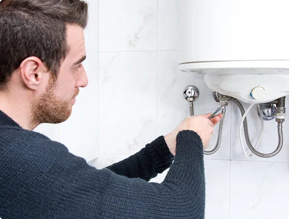 Technician repairing connections beneath a water heater