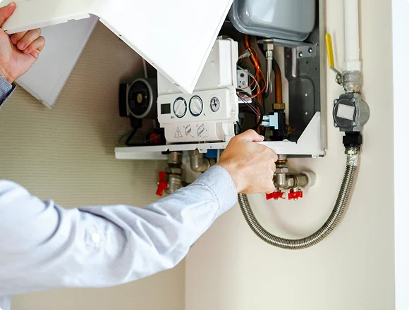 Technician servicing an open wall-mounted boiler