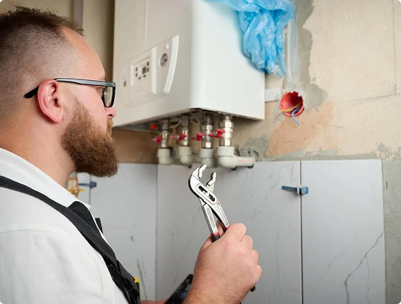 Plumber preparing to service a wall-mounted boiler